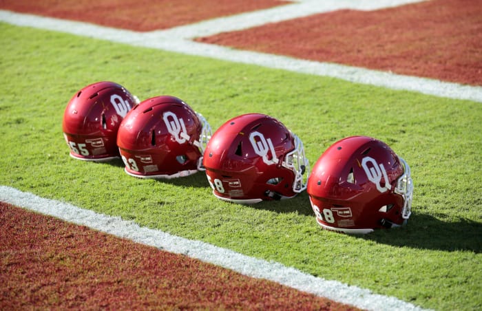 Four Oklahoma Sooners helmets lined up on the field before a football game.