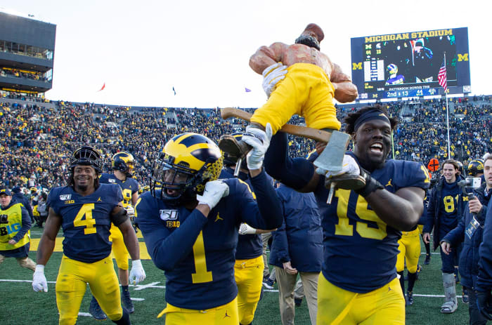 Ambry Thomas helps hoist a trophy after Michigan's win over Michigan State.