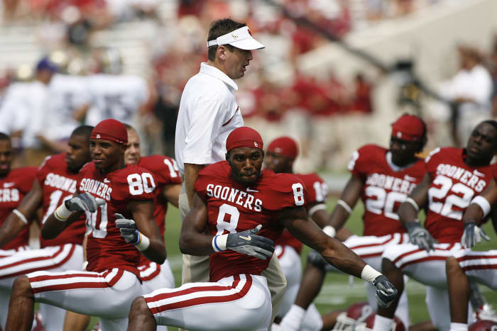 Bob Stoops walking by his players as they stretch.