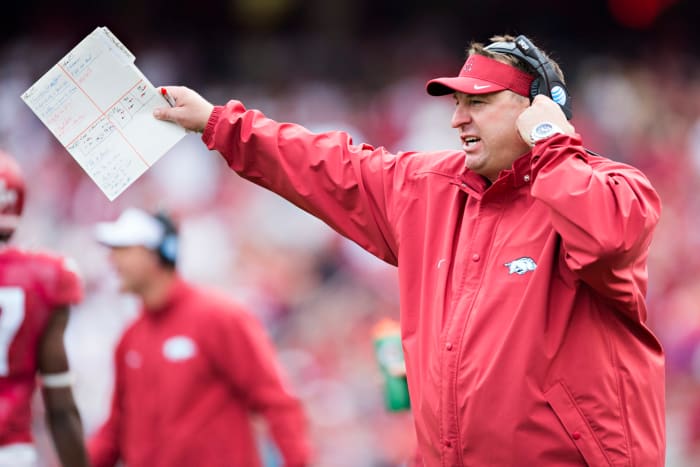 Bret Bielema pointing while wearing a red Arkansas jumpsuit.