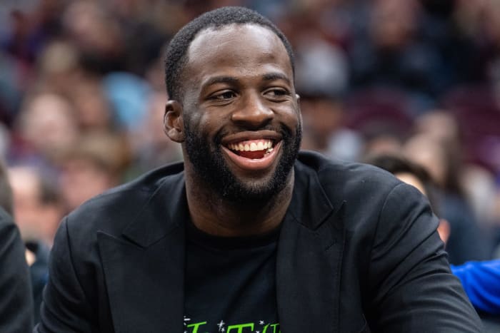 A closeup of a smiling Draymond Green sitting on the bench.