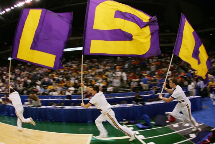 lsu cheerleaders run onto the field holding 'lsu' flags