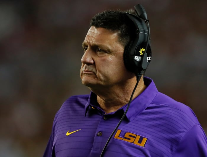 LSU football coach Ed Orgeron wearing a headset and a concerned look.