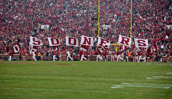 A picture of Oklahoma's cheerleaders running with flags that spell out "Sooners".