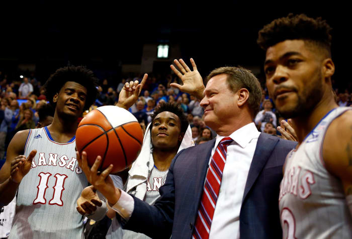 Bill Self holding a basketball with Josh Jackson, Devonte' Graham and Frank Mason III.
