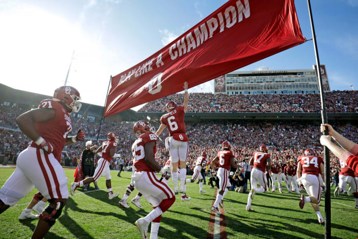 Oklahoma Sooners players running onto the field.