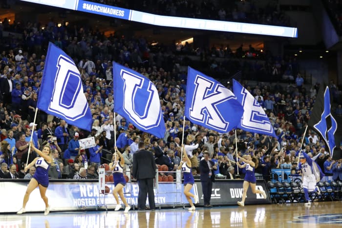 Duke cheerleaders carry school flags onto the court.
