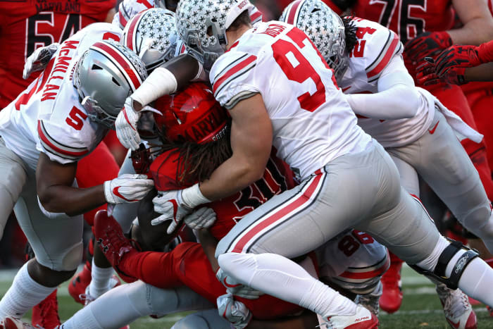 Ohio State football players including Raekwon McMillan tackling a Maryland player.