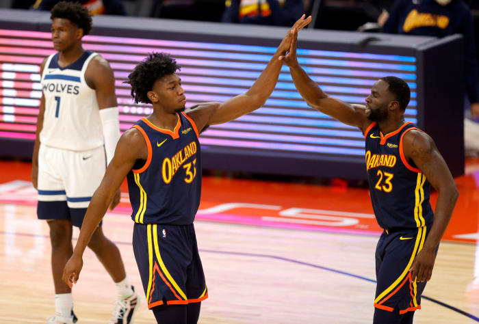 James Wiseman high-fives Draymond Green of the Warriors.
