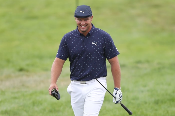 Bryson DeChambeau walks with his broken driver.