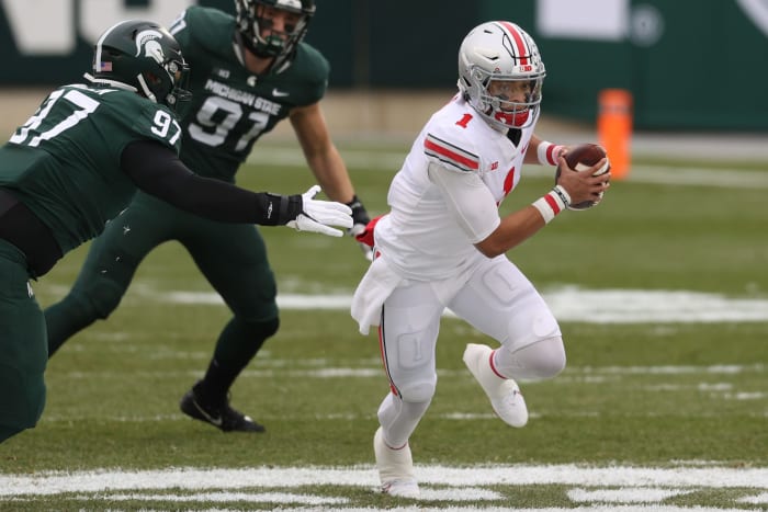 Justin Fields #1 of the Ohio State Buckeyes gets around a tackle