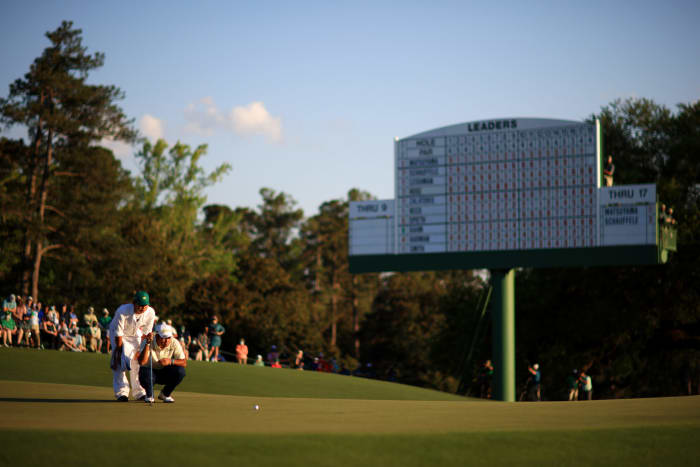 Hideki Matsuyama and his caddie line up a putt at The Masters.