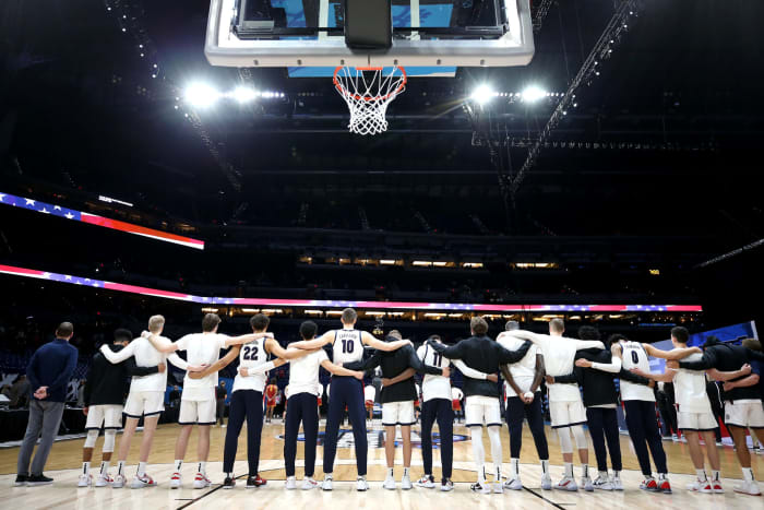 Gonzaga players linking arms and standing for the national anthem.