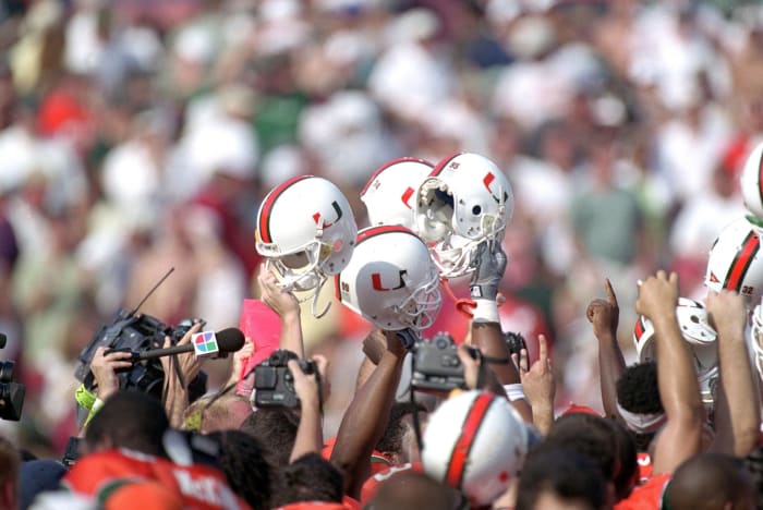 Miami football helmets held up by Hurricanes players.