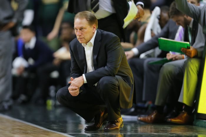 Tom Izzo crouching on Michigan State's sideline.