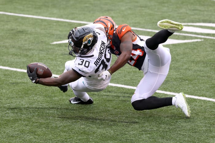 Jacksonville Jaguars running back James Robinson reaches with the ball as he is tackled.