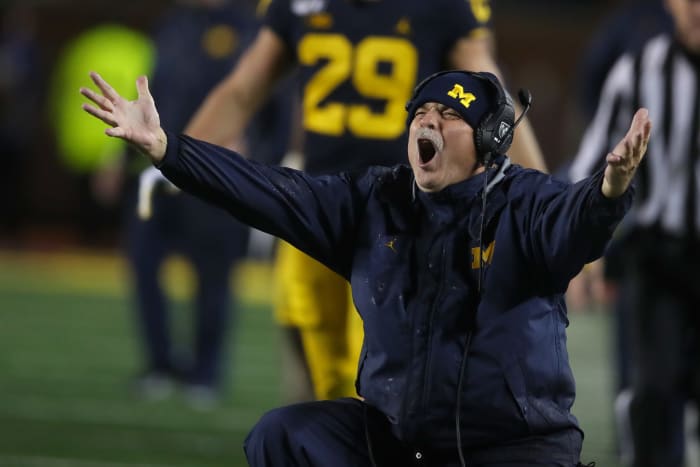 Michigan football coach Don Brown arguing a call with his arms spread open.