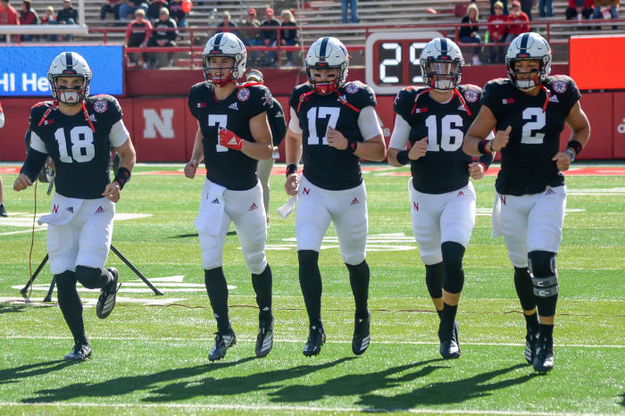 Nebraska football quarterbacks including Adrian Martinez and Luke McCaffrey running onto the field.
