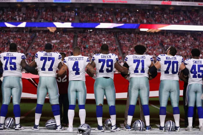 A photo of the Dallas Cowboys locking arms during the National Anthem, including Dak Prescott and his offensive line.