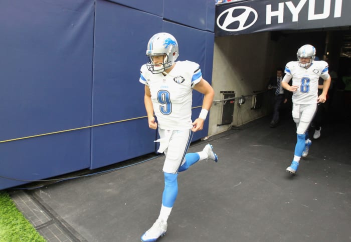 Detroit Lions quarterbacks Matthew Stafford and Dan Orlovsky run onto the field.