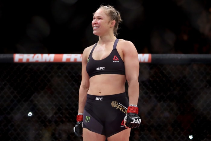 Ronda Rousey in the octagon with a huge smile on her face.