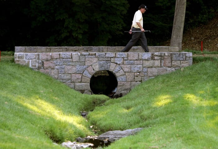 Phil Mickelson walks across a bridge at Winged Foot.