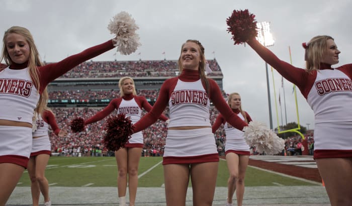The Oklahoma Sooners cheerleaders cheering during a football game.