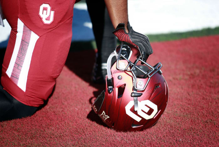 An Oklahoma Sooners player resting his helmet on the field.