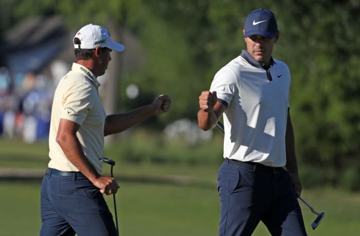 Chase Koepka and Brooks Koepka celebrate a putt.