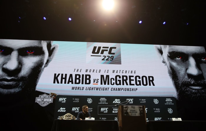 Khabib sitting at a podium speaking during a promo for his fight against Conor McGregor.