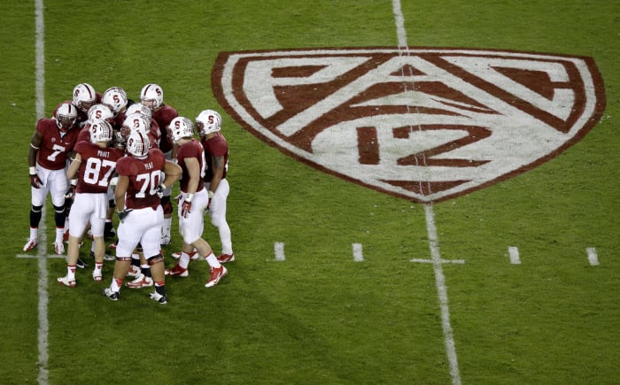 Stanford's football team huddled up on the field next to a PAC-12 logo.
