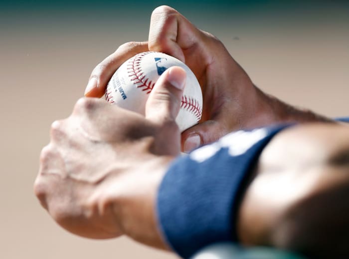 A baseball player holding a baseball with the MLB's logo on it.