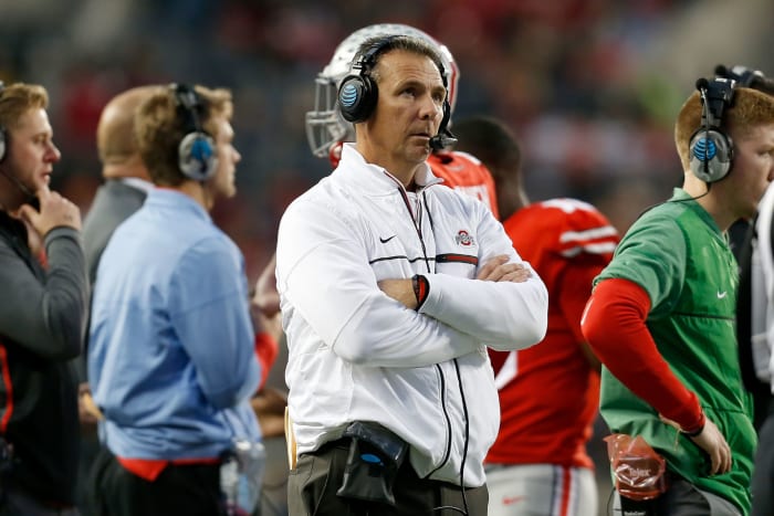 A closeup of Urban Meyer with his arms crossed on the sideline during an Ohio State football game.