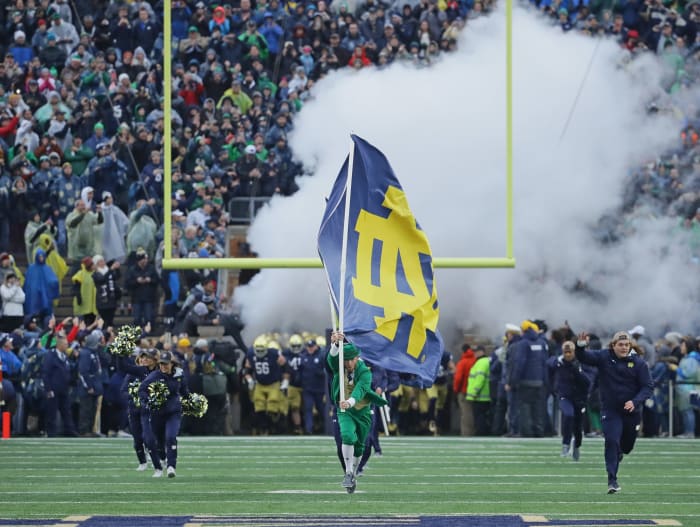 Notre Dame's mascot leading the football team onto the field.