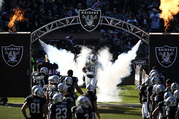 Oakland Raiders players running through smoke onto the field.