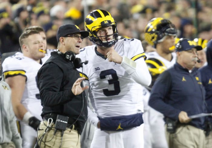 Head coach Jim Harbaugh of the Michigan Wolverines talks with quarterback Wilton Speight.