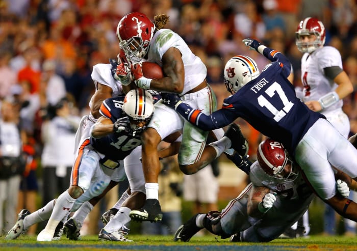 Derrick Henry of the Alabama Crimson Tide rushes against Carlton Davis #18 and Kris Frost #17 of the Auburn Tigers at Jordan Hare Stadium.