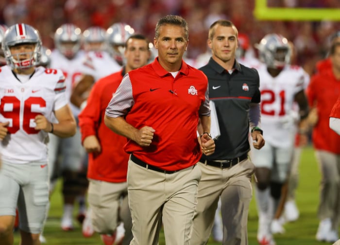 Urban Meyer running onto the field with his Ohio State football players.