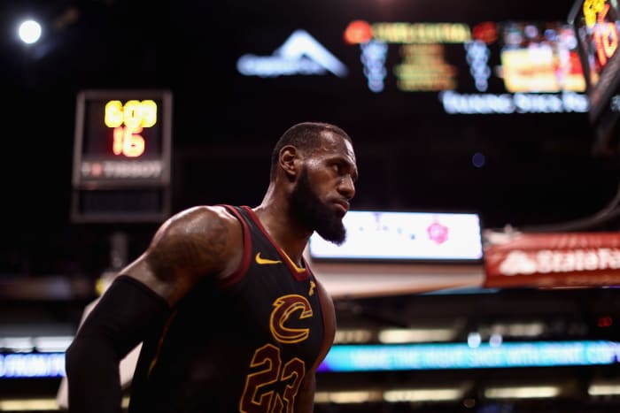 LeBron James walking onto the court in his black Cleveland Cavaliers uniform.