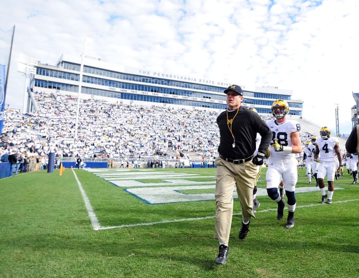 Jim Harbaugh head coach of the Michigan Wolverines runs onto the field prior to the game against the Penn State Nittany Lions at Beaver Stadium.