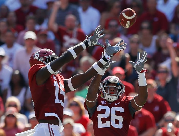 Alabama football players intercepting a pass.