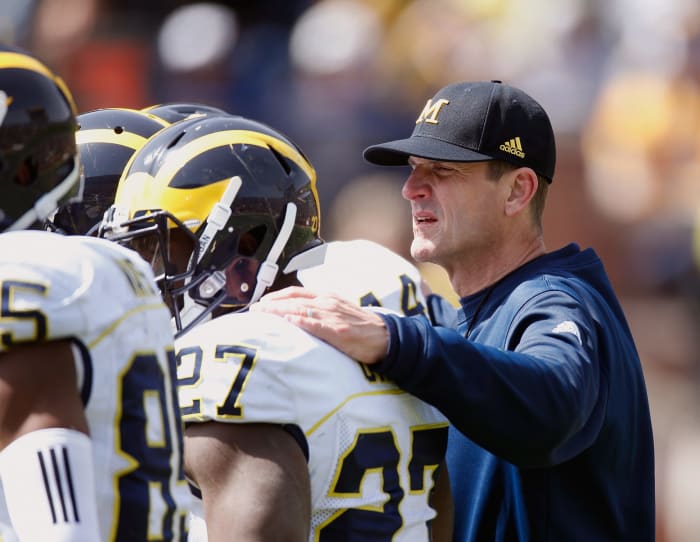 Head coach Jim Harbaugh of the Michigan Wolverines listens in on an offensive huddle during the Michigan Football Spring Game.