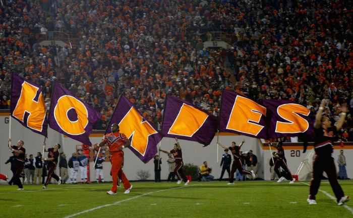 Virginia Tech cheerleaders holding flags that spell out Hokies.