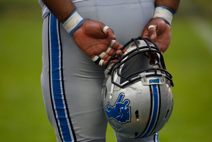 A Detroit Lions player holding his helmet behind his back before a game.