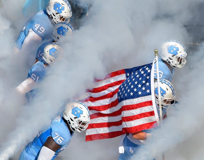 North Carolina players enter the game through smoke.