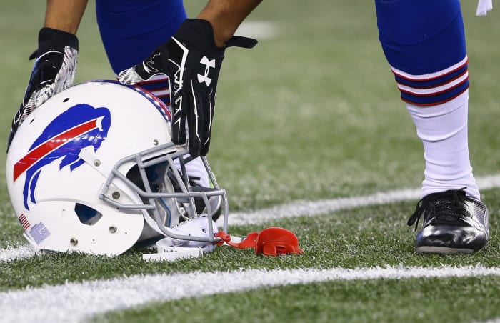 A Buffalo Bills player picking up his helmet off the field.