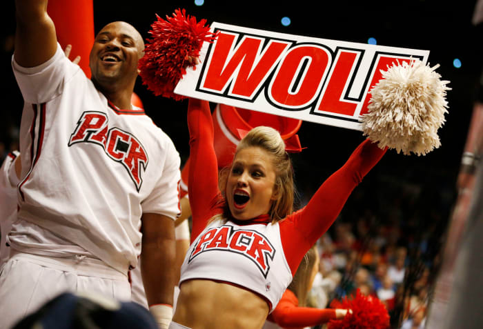 An NC State cheerleader holding up a sign.