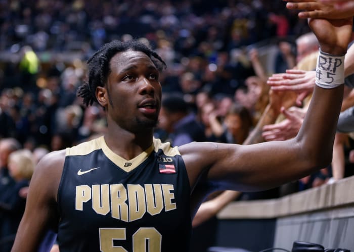 Purdue star Caleb Swanigan high-fives a fan while leaving the court after a game.