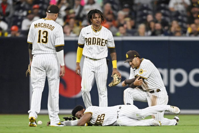 SAN DIEGO, CA - JULY 7: Jurickson Profar #10 of the San Diego Padres (C) lies on the ground as Manny Machado #13 (L), C.J. Abrams #77 and Trent Grisham #2 look on during the fifth inning of a baseball game against the San Francisco Giants July 7, 2022 at Petco Park in San Diego, California. Profar was injured on the play. (Photo by Denis Poroy/Getty Images)