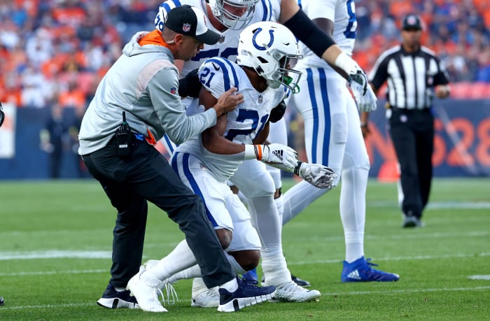DENVER, COLORADO - OCTOBER 06: Nyheim Hines #21 of the Indianapolis Colts is helped to his feet by #79 after being hit during a game against the Denver Broncos at Empower Field At Mile High on October 06, 2022 in Denver, Colorado. (Photo by Justin Tafoya/Getty Images)